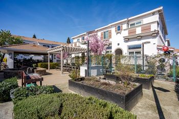 A white building with a red roof and a garden in front.